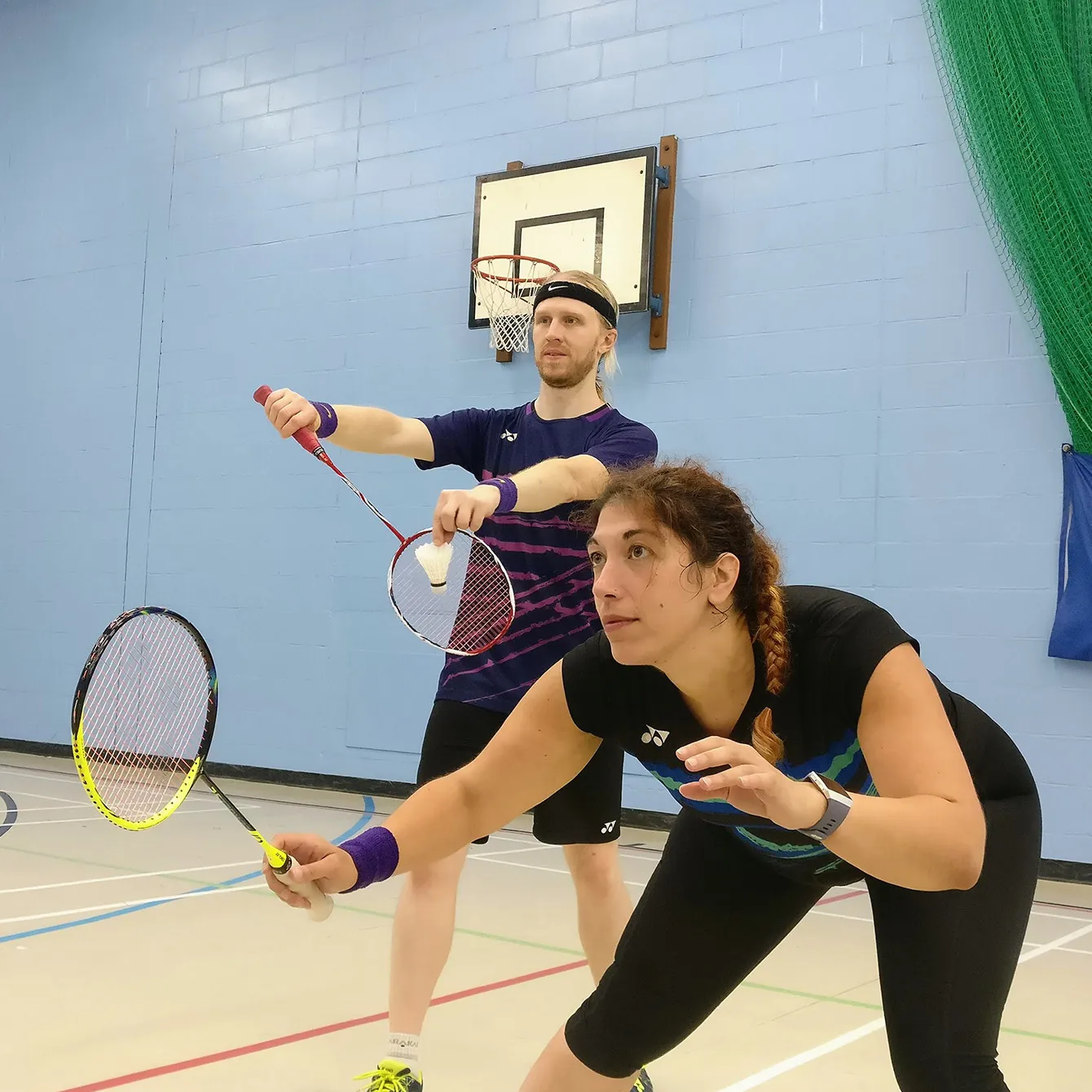 A mixed pair of badminton players from Broadlands, with the man just about to serve.